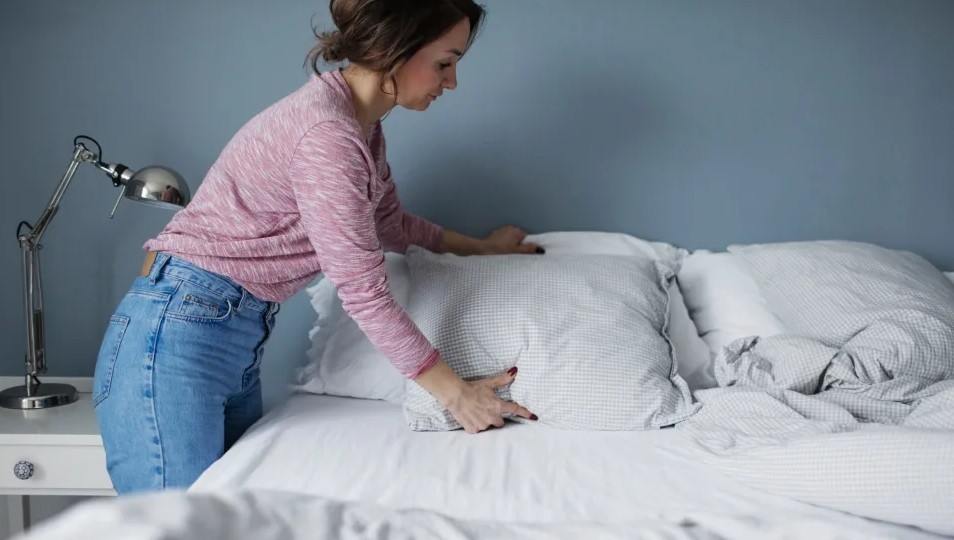 γυναίκα στρώνει κρεβάτι μαξιλάρι